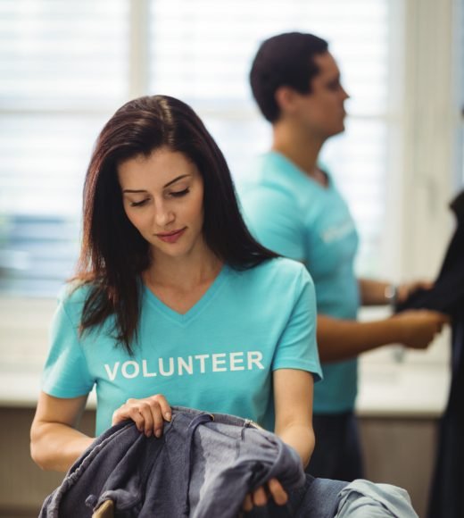 Beautiful female volunteer checking clothes in workshop